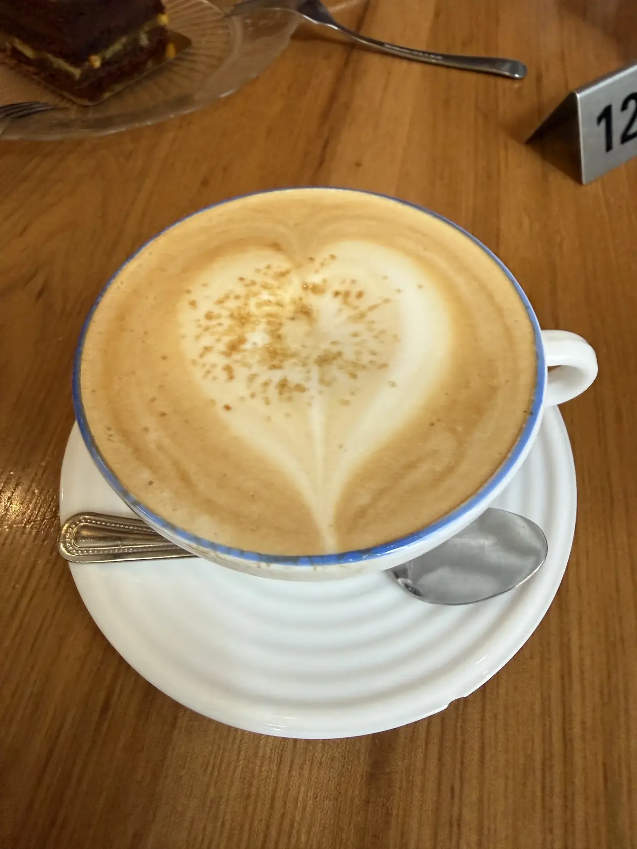 Cappuccino with heart-shaped latte art and cinnamon dusting, on a saucer