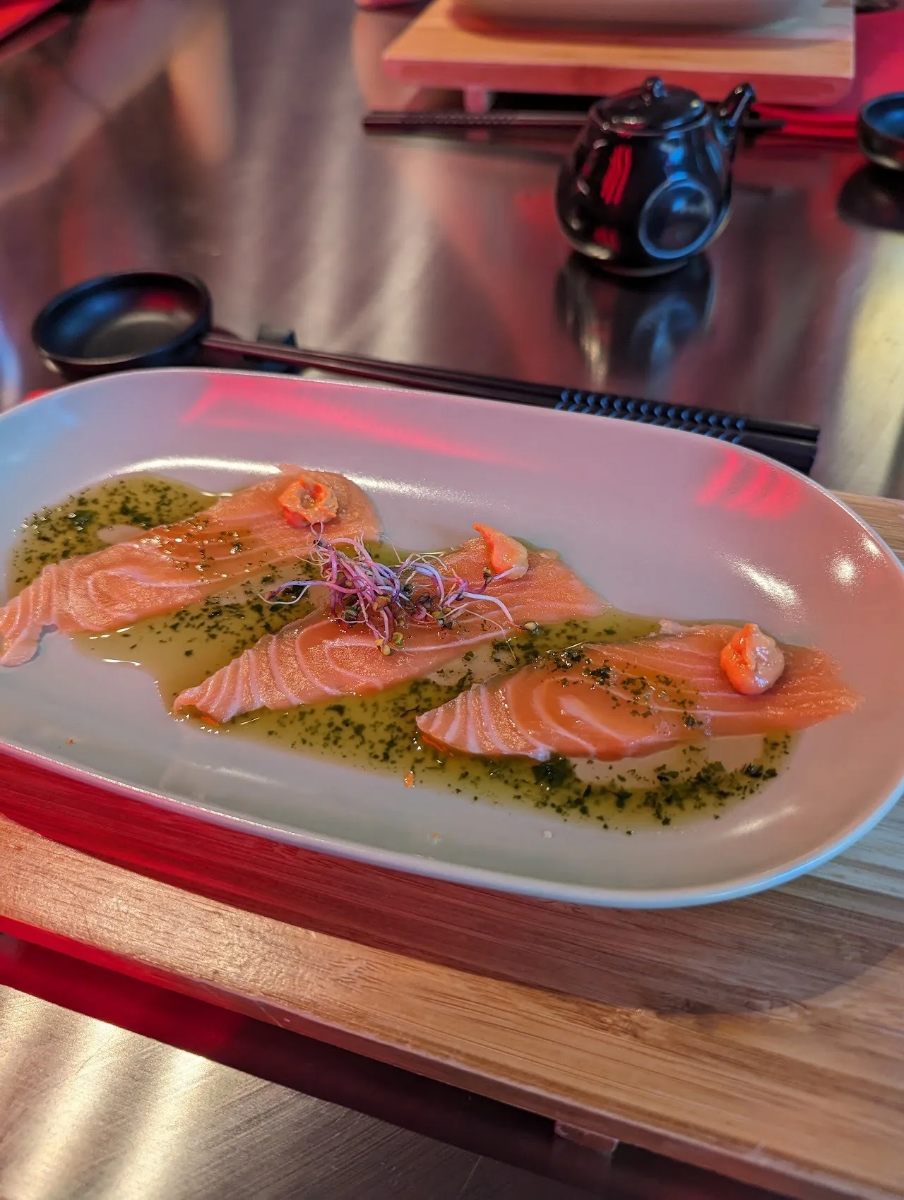 Slices of salmon with green sauce on a white oval dish