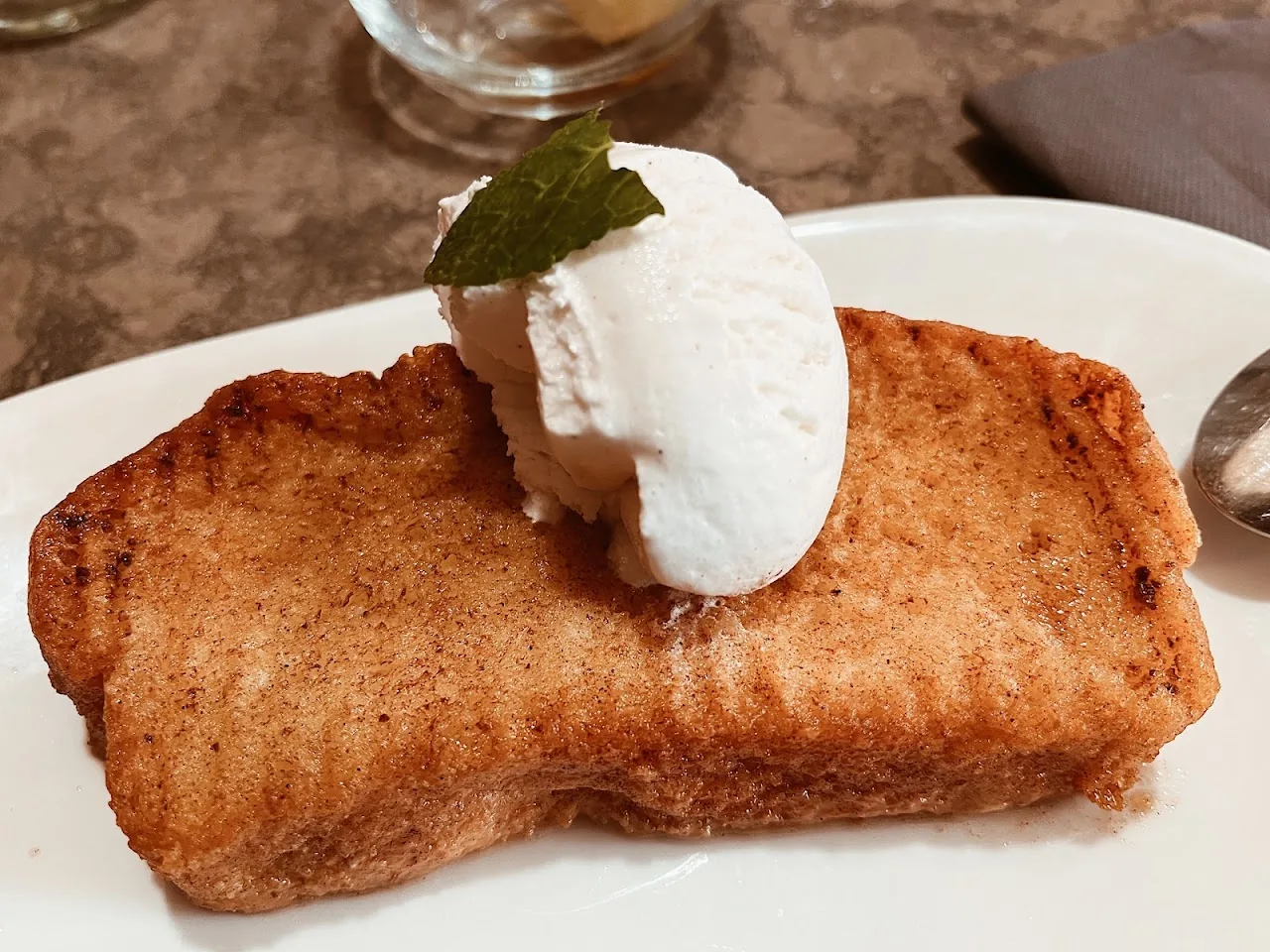 A caramelized bread dessert topped with ice cream and mint