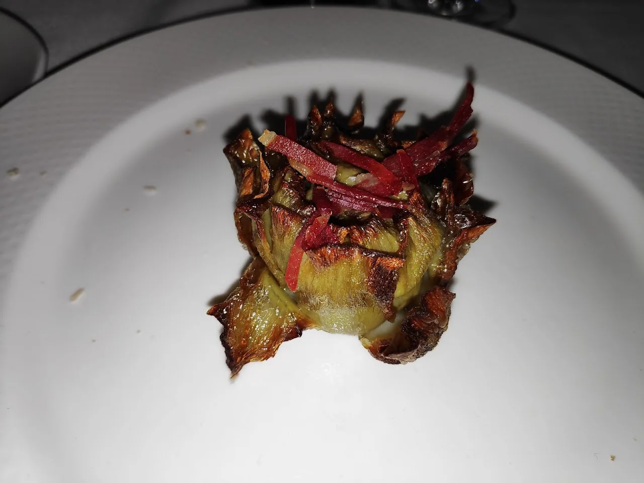 A charred grilled artichoke half on a plate
