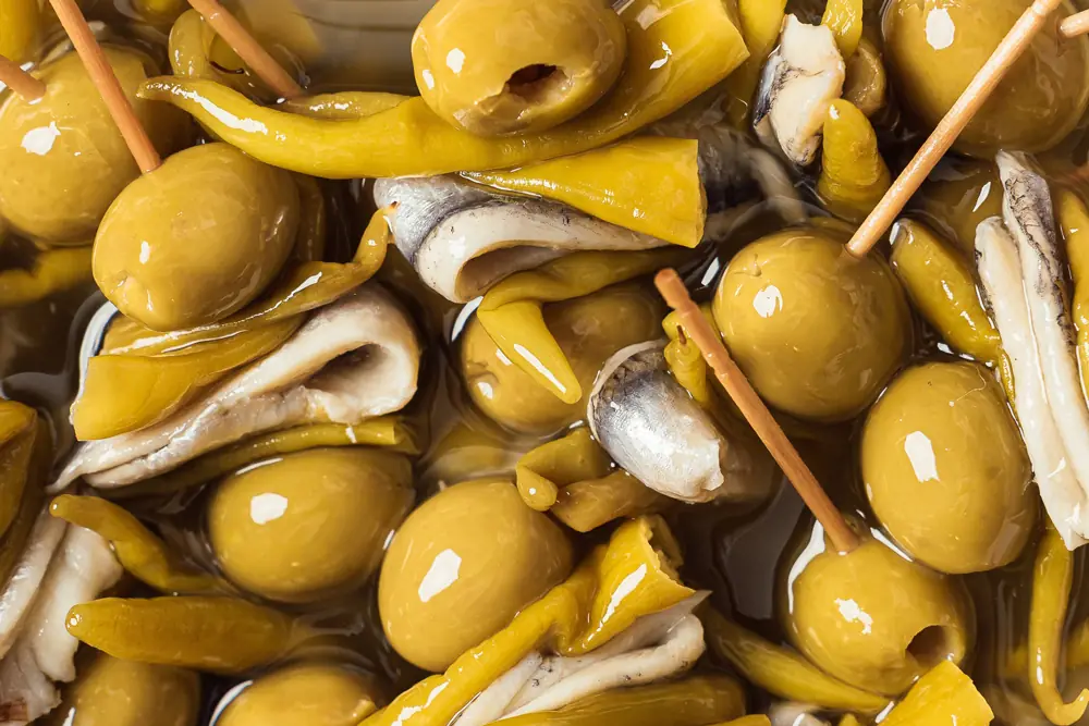 Marinated green olives skewered with anchovy fillets and pickled guindilla peppers, close-up, at Semon