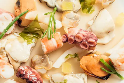 A close-up seafood spread of octopus, mussels, and shellfish with herb garnish at Semon