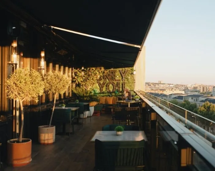 A terrace with trees and seating overlooking the city at dusk