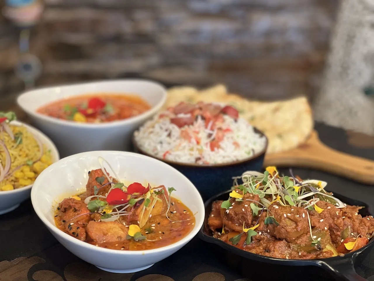 A spread of curry bowls with rice and naan