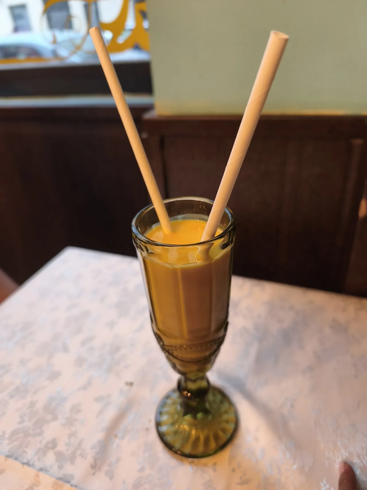 A glass of orange lassi with two straws