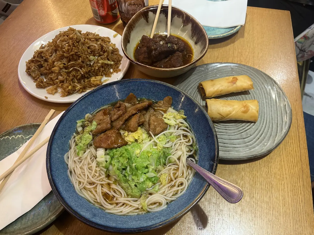 Table spread of fried rice, braised meat in broth, noodle soup with pork and cabbage, and spring rolls
