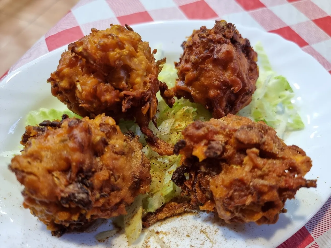 Four fried pakora fritters on a bed of lettuce