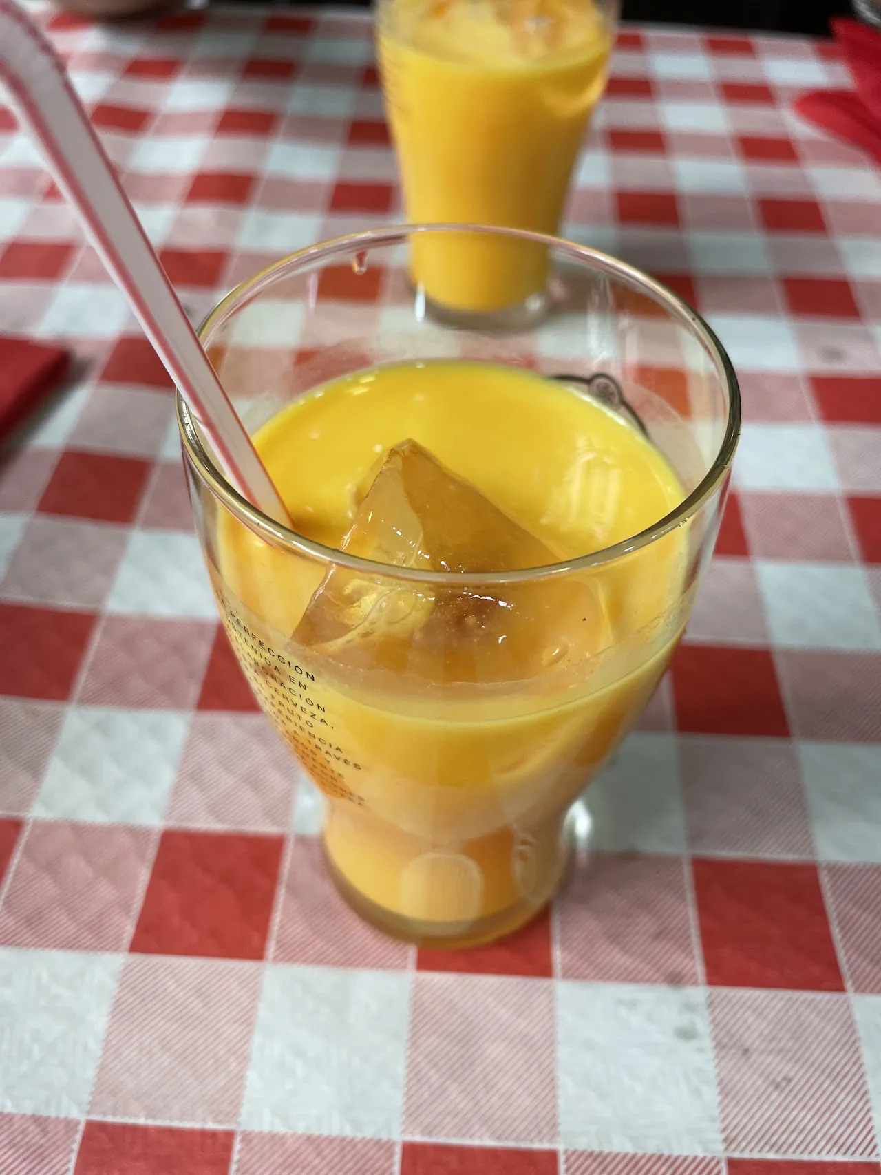 A glass of mango lassi with a straw