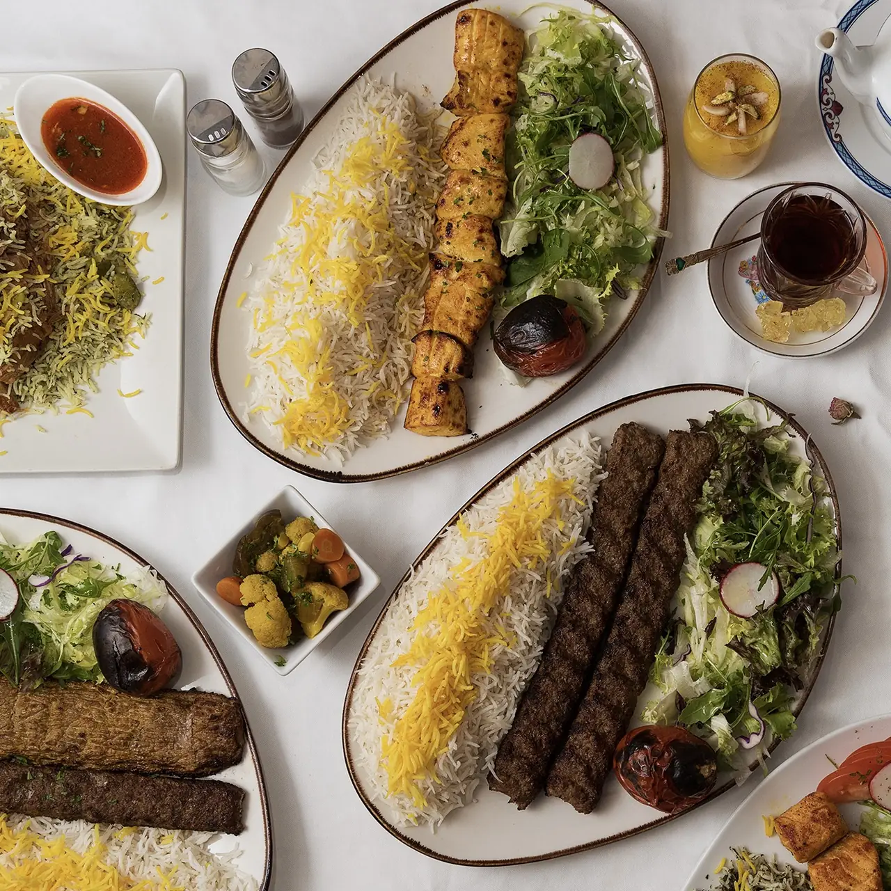 Grilled chicken and beef kebab platters over saffron rice with fresh salad and grilled tomato, served with tea and pickled vegetables at Restaurante Shiraz
