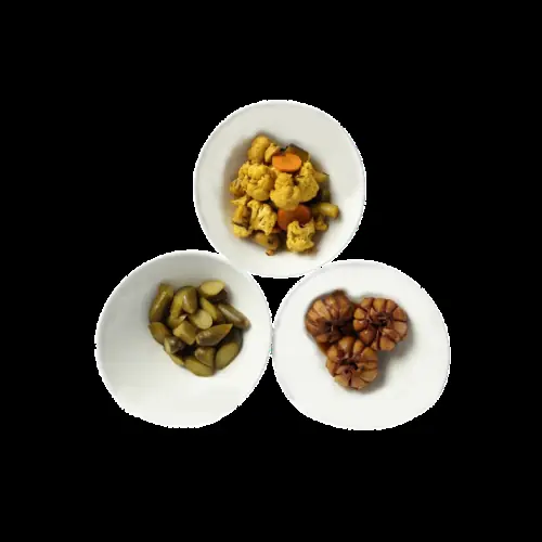 Three small dishes of pickled sides at Restaurante Shiraz: cauliflower and carrot, green pickles, and pickled garlic cloves