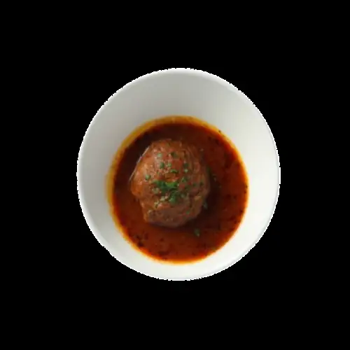 A meatball in red tomato sauce garnished with herbs, served in a white bowl at Restaurante Shiraz