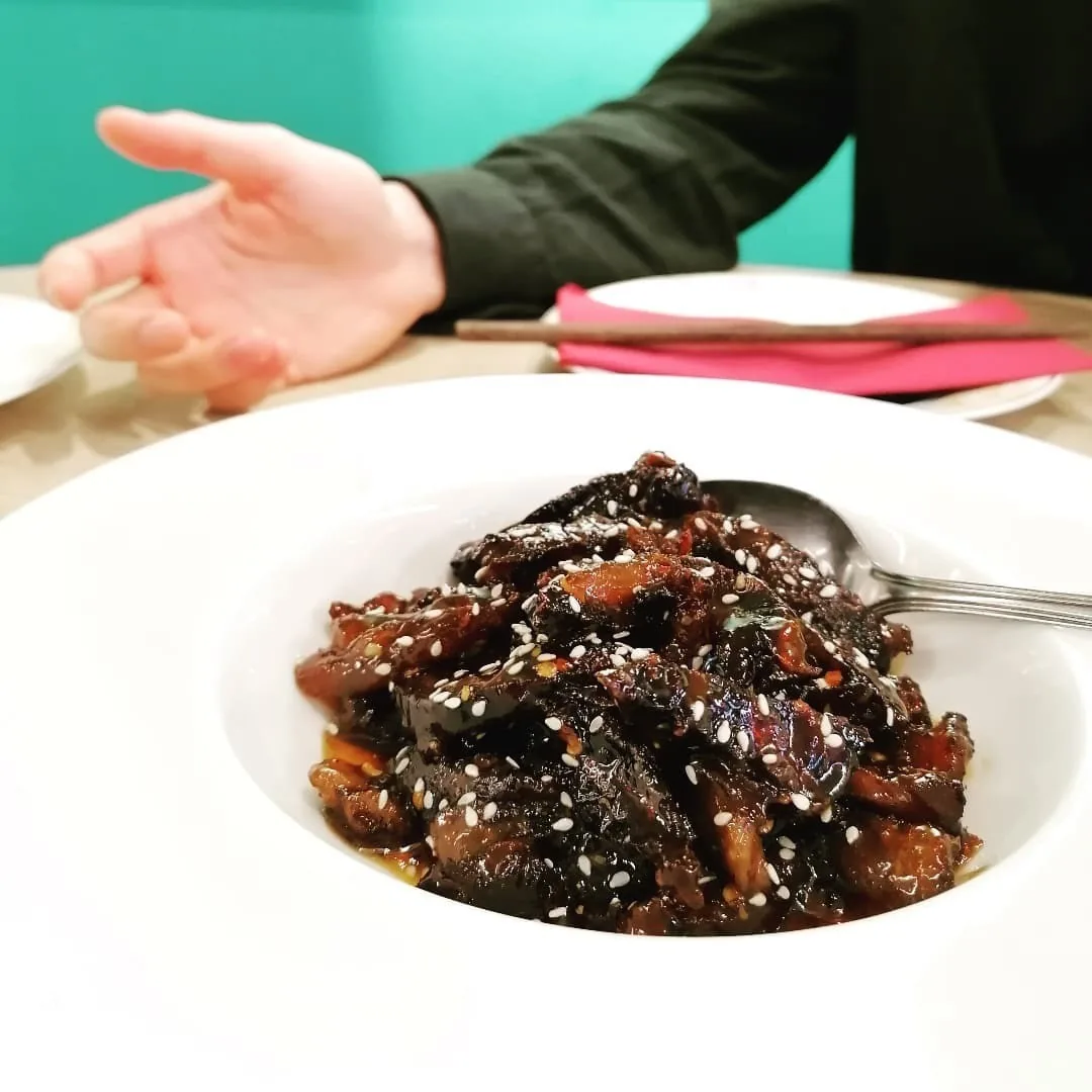 A bowl of dark braised meat sprinkled with sesame seeds