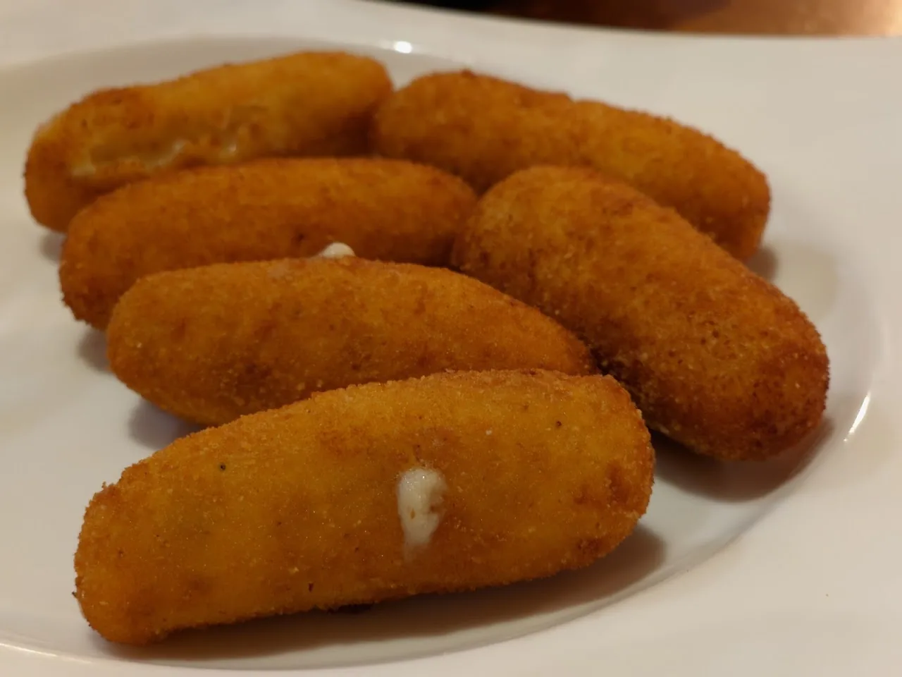 Five golden breaded croquettes on a plate