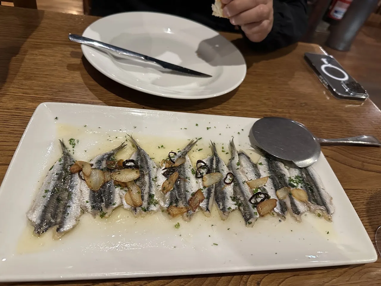 A row of marinated anchovy fillets on a white platter