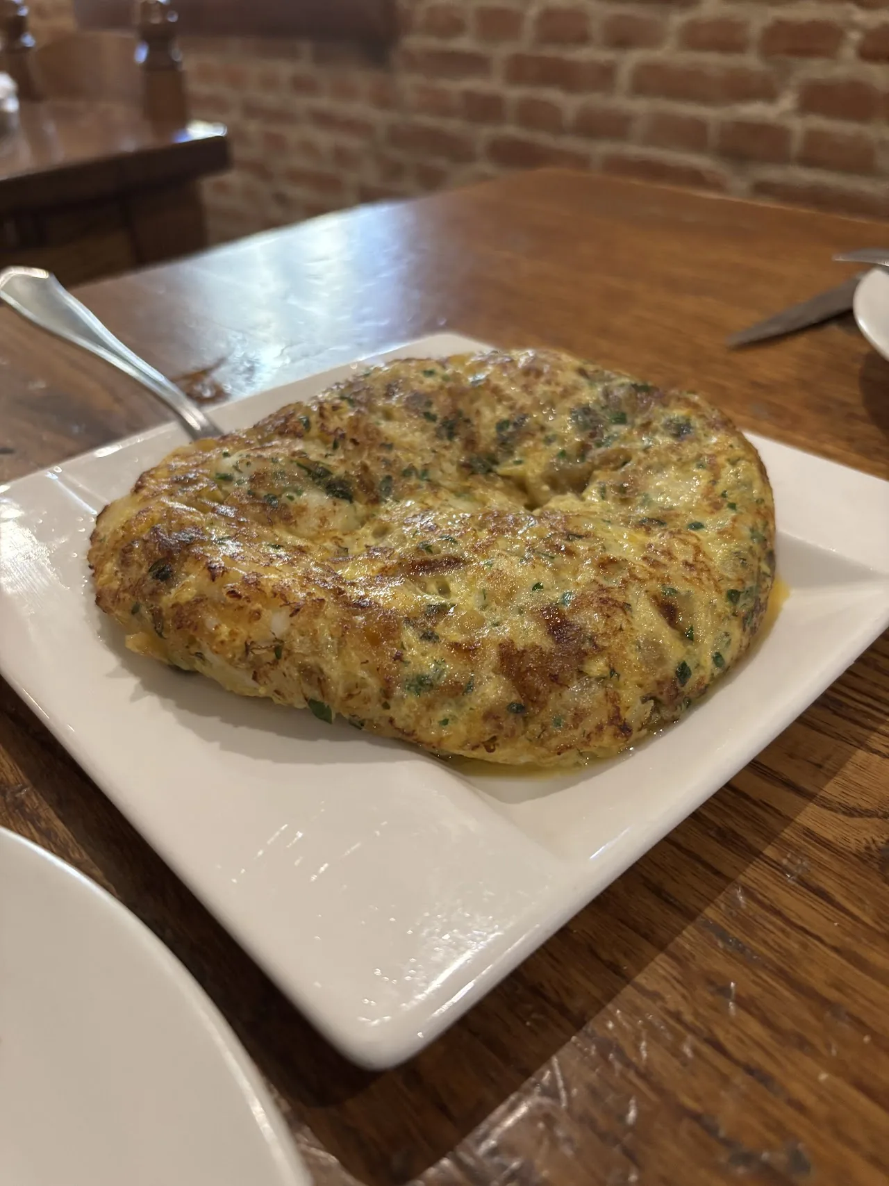 A thick Spanish tortilla on a square plate