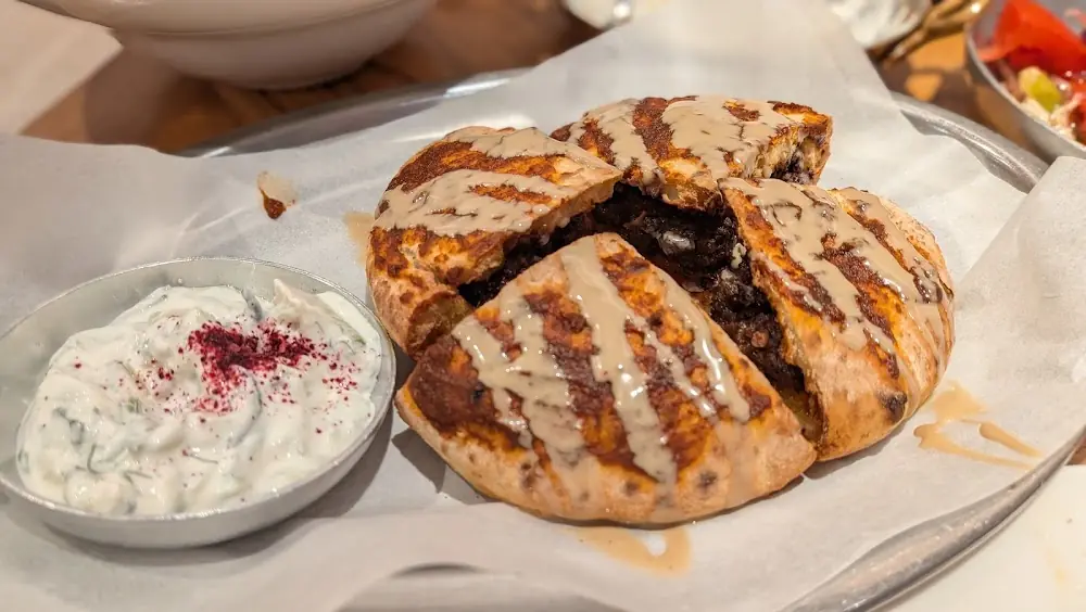 Grilled stuffed flatbread cut into quarters, served with a yogurt-herb dip at Silan