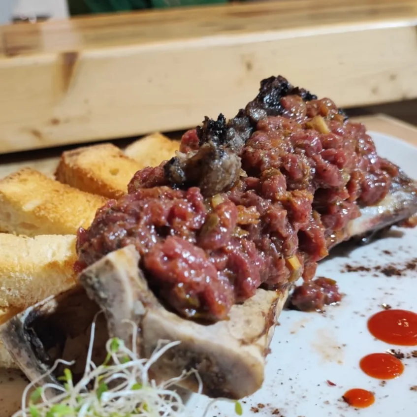 Bone marrow topped with beef tartare on toast
