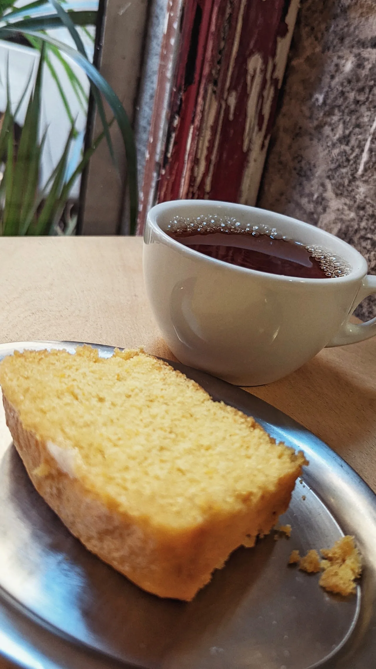 A slice of pound cake beside a cup of tea