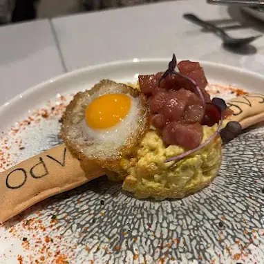 Plated dish with fried quail egg, diced tuna tartare and mashed avocado on a patterned plate