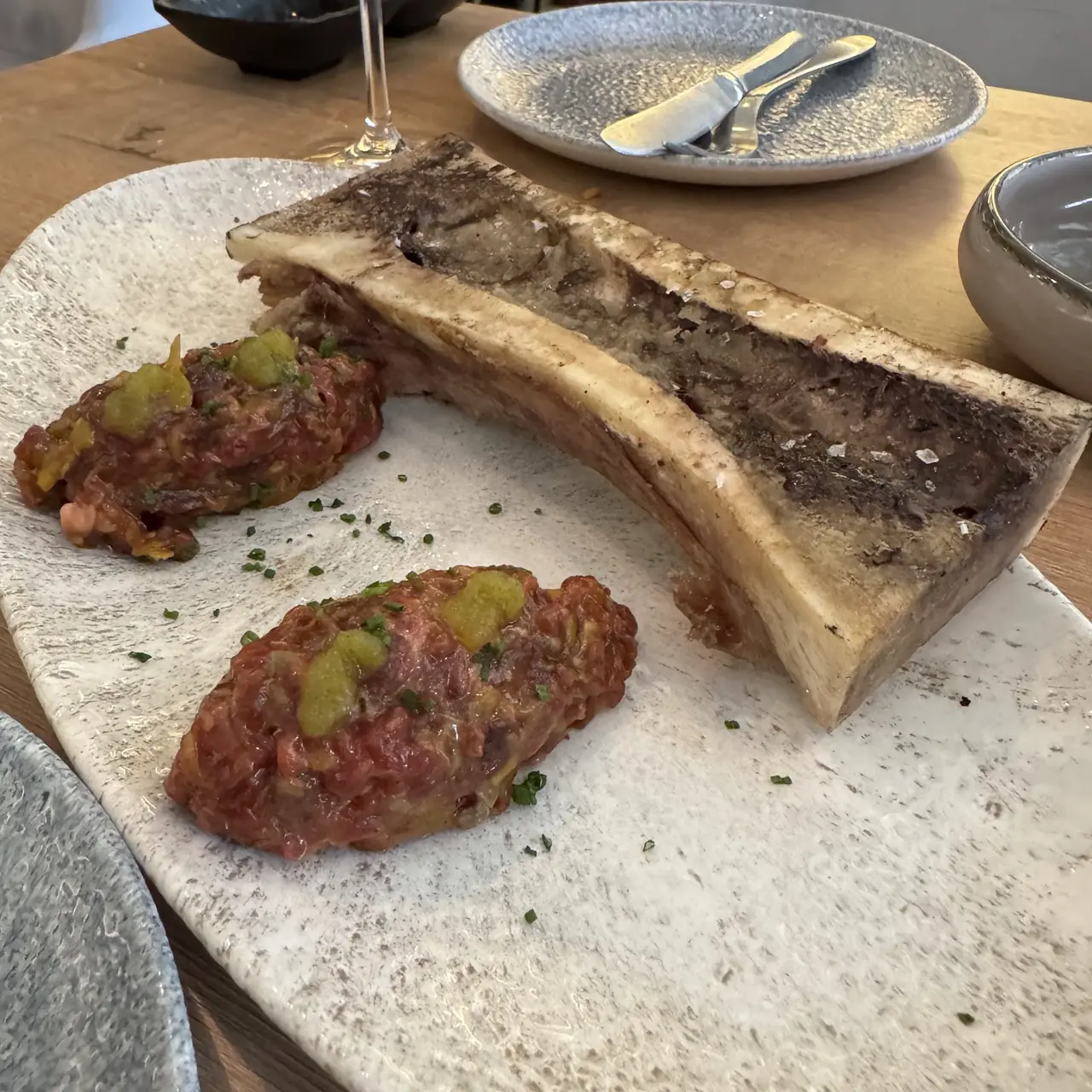 Roasted bone marrow served with two portions of beef tartare on a stone board