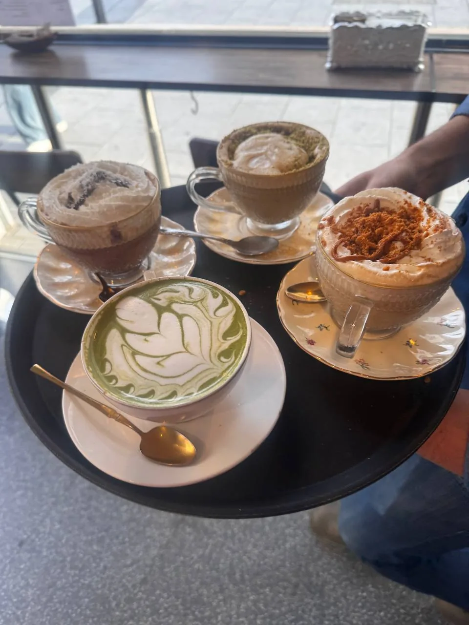 A tray of four assorted coffee drinks with latte art on top