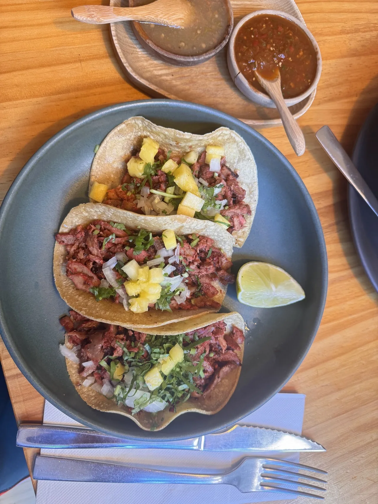 Three soft tacos with shredded meat and pineapple on a blue plate