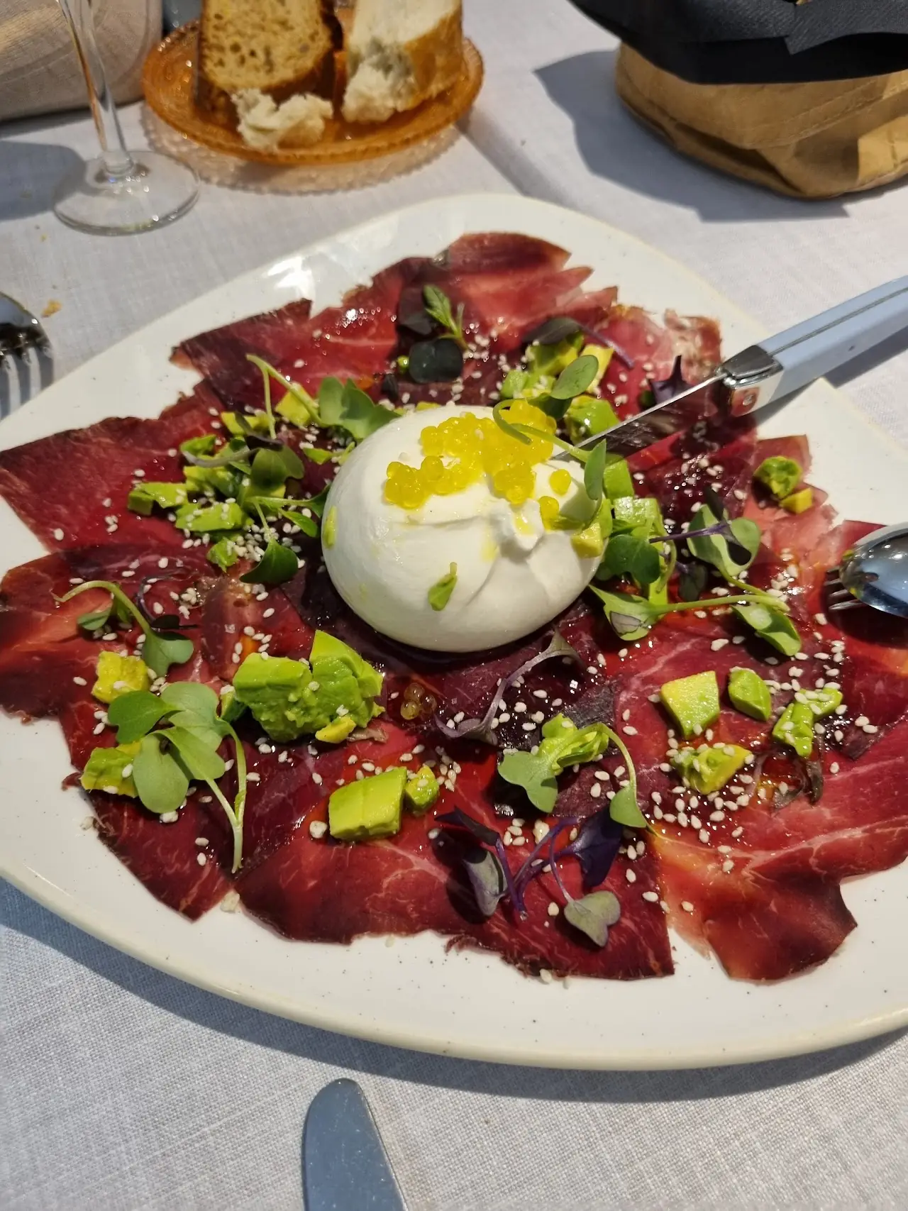 Beef carpaccio topped with burrata, rocket and toasted seeds.