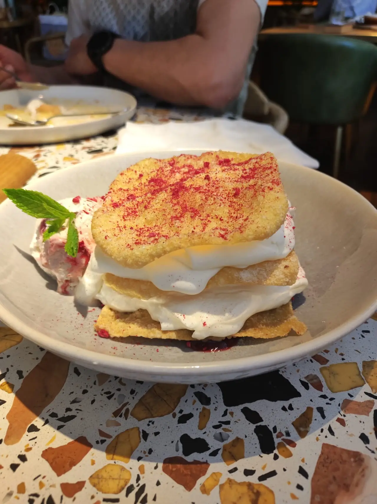 Layered millefeuille dessert with cream and red berry powder.