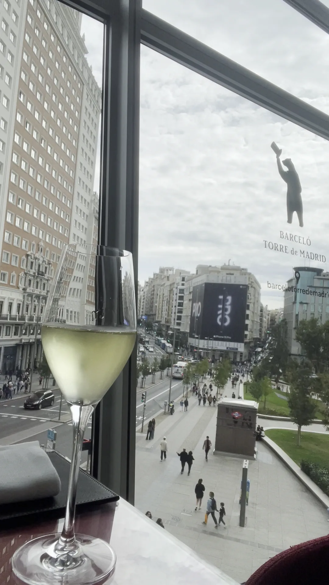 A cocktail in a coupe glass on a windowsill overlooking the city