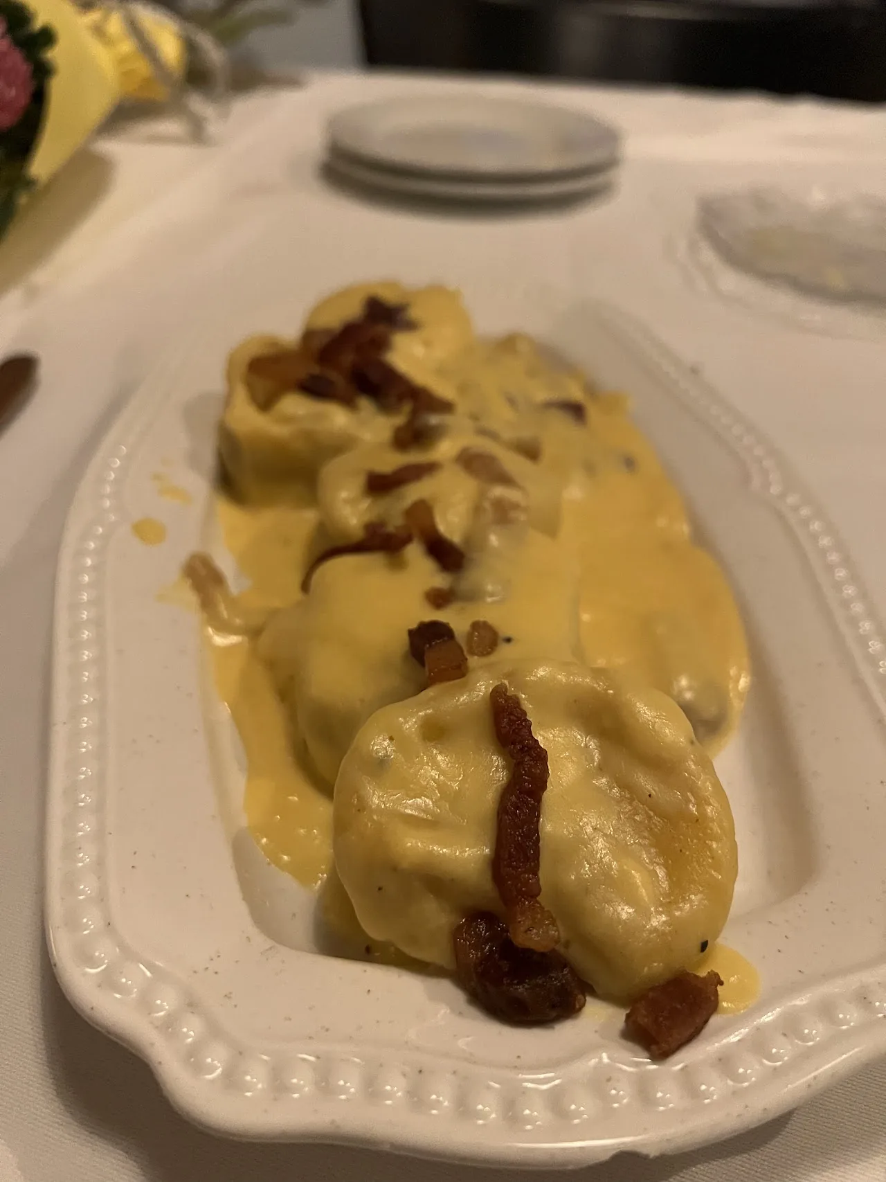 Ravioli in a creamy sauce topped with crispy pancetta shavings