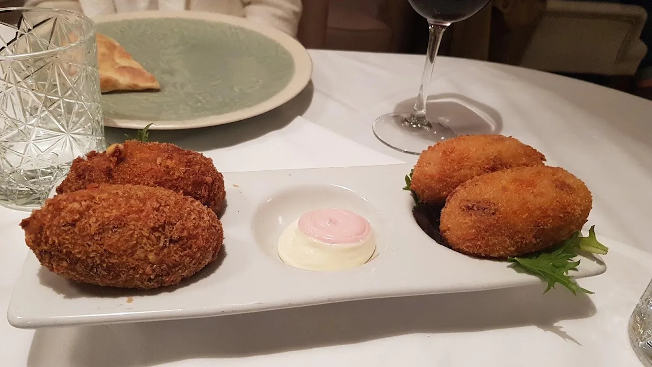 A plate of fried croquettes with a dollop of sauce and a small salad