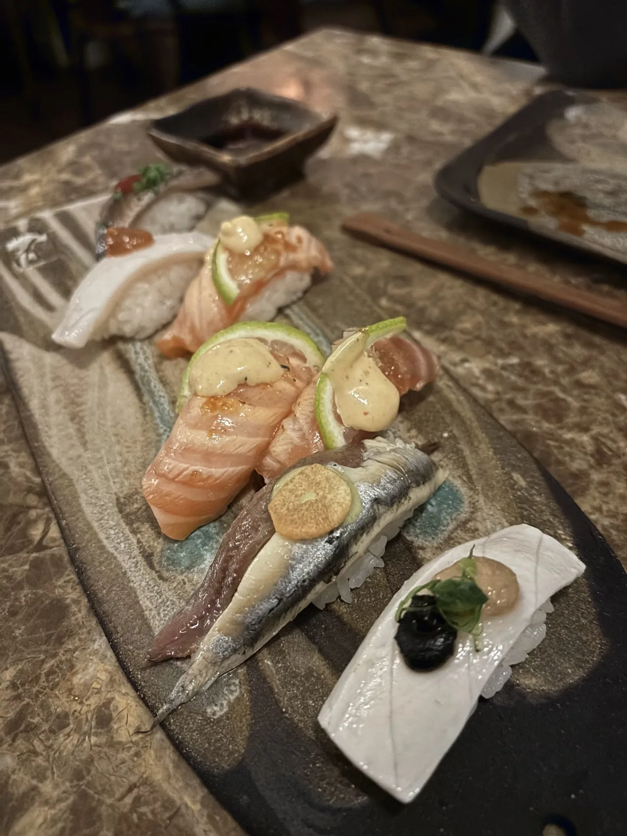 A stone platter of assorted sashimi slices with citrus and dipping sauce