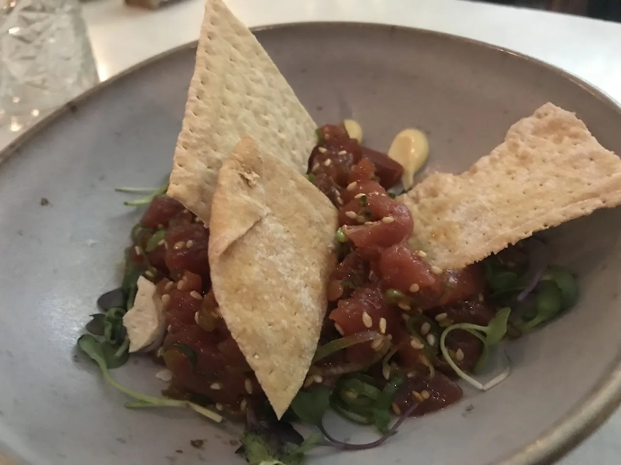 A tuna tartare on a plate garnished with crispy wonton chips