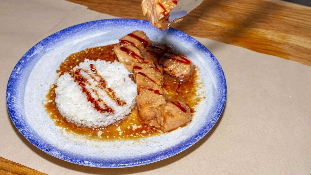 Rice and glazed pieces of meat on a blue-rimmed plate