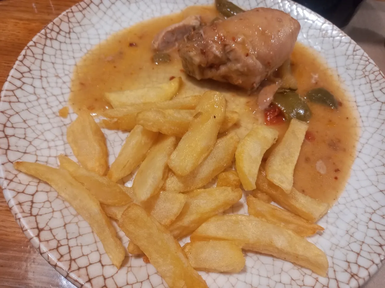 A roasted chicken leg in sauce with a side of French fries