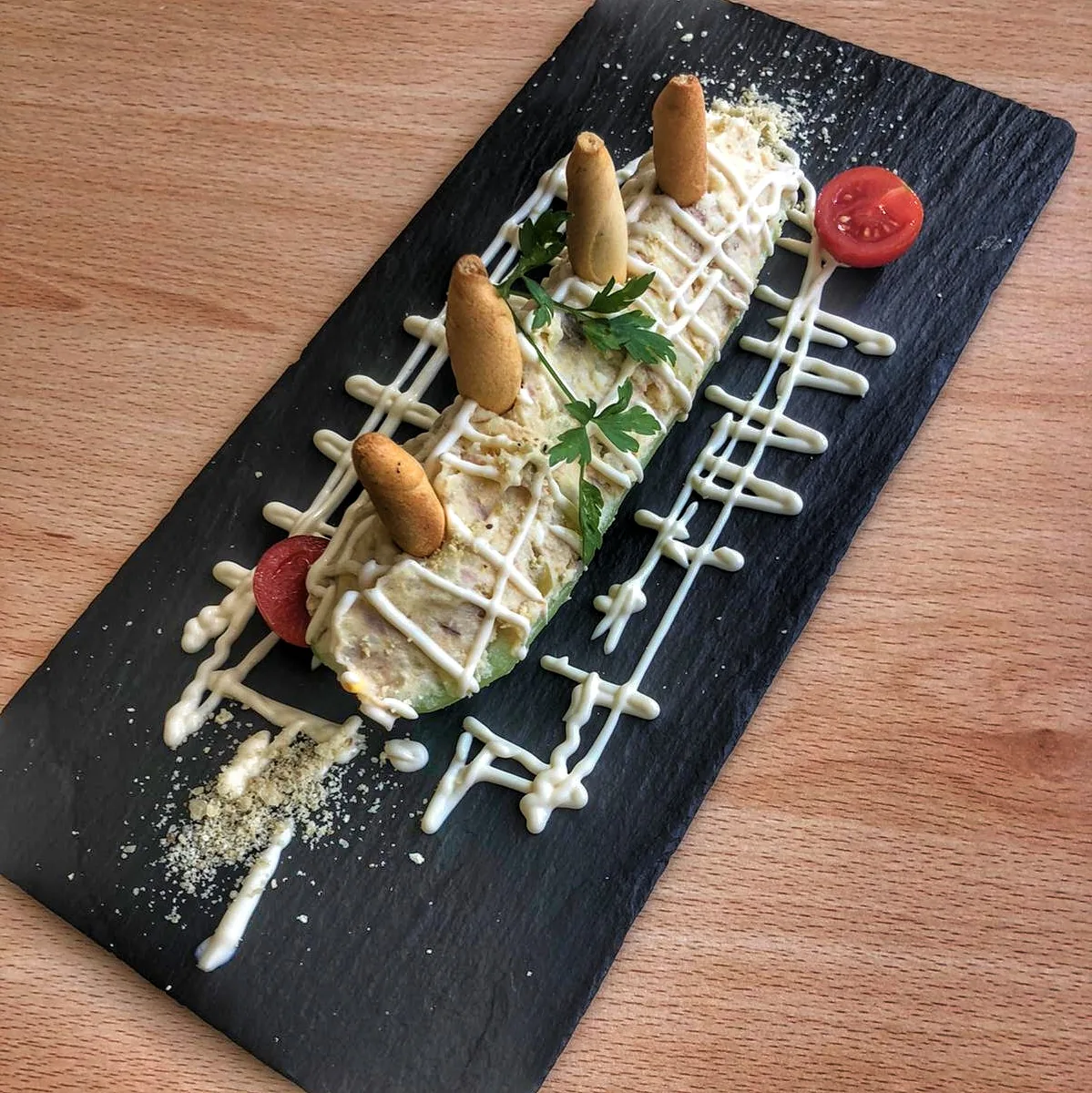 Toasted bread pieces topped with cheese and herbs on a slate board with cherry tomatoes
