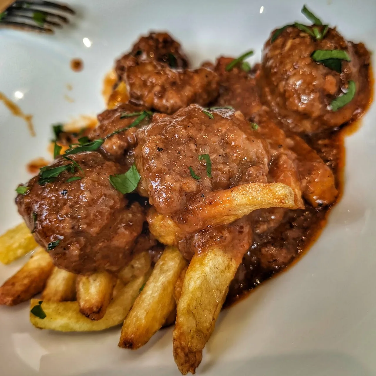 Meatballs in tomato sauce served over french fries
