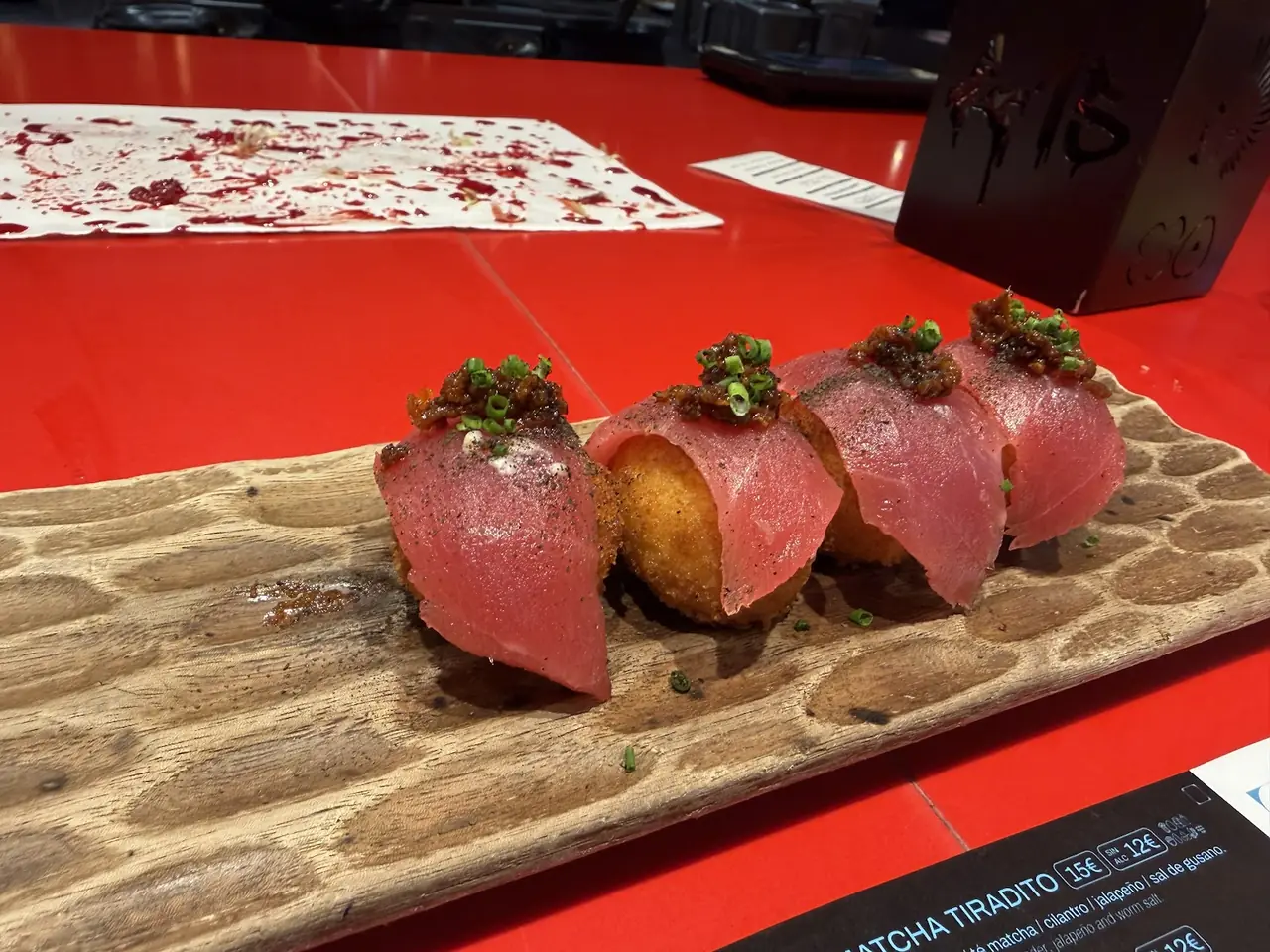 Four tuna-topped fried croquettes with chili crisp and scallion on wooden board