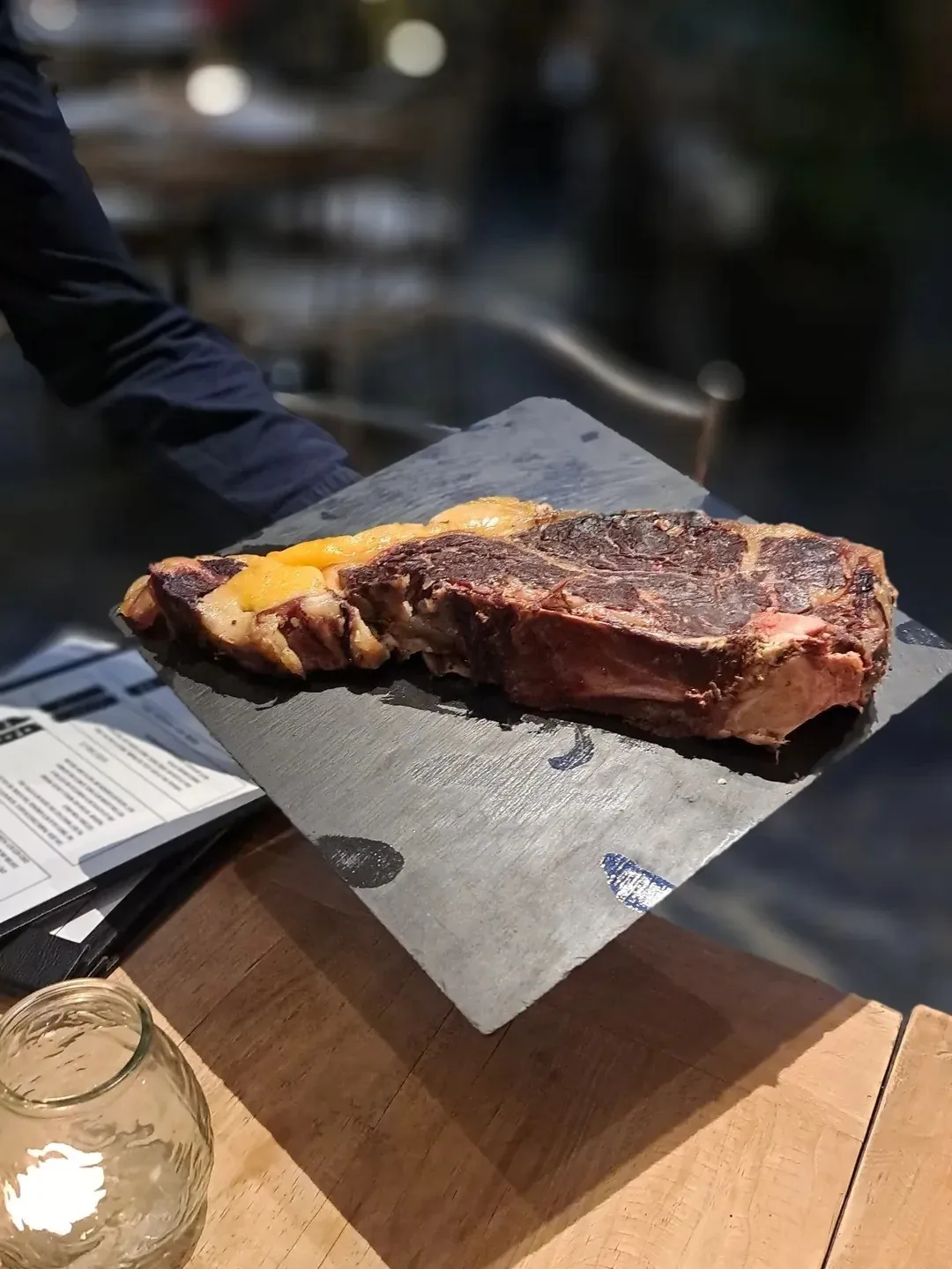 A grilled beef steak on a slate board on a wooden table