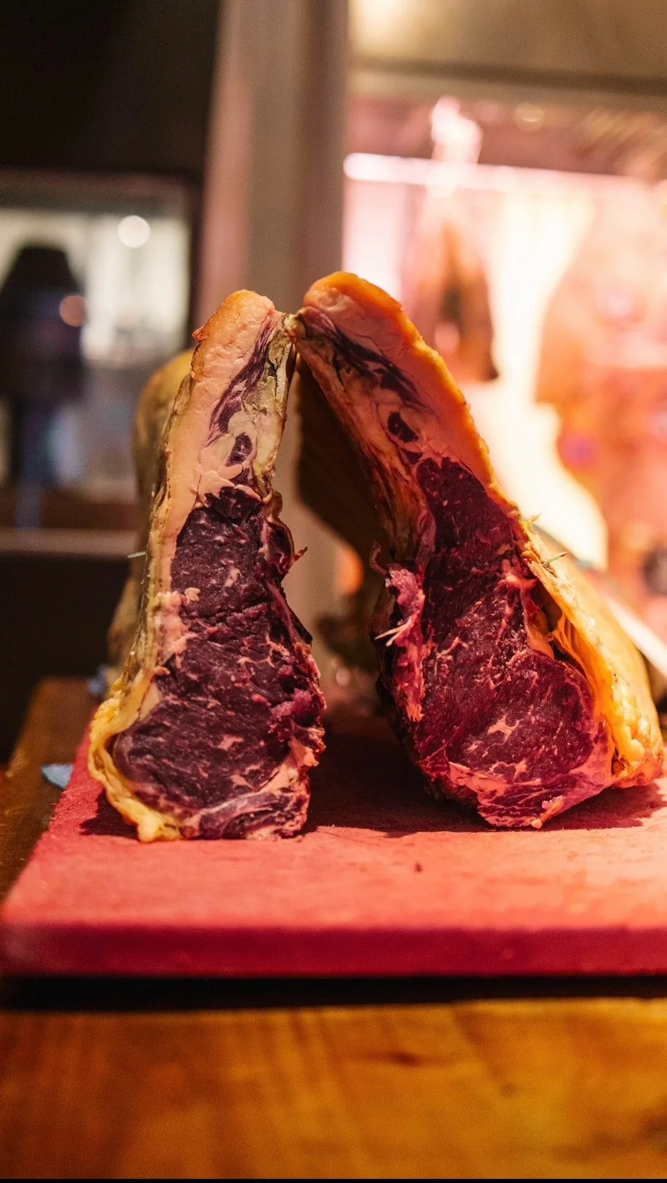Two halves of a large bone-in beef cut standing in front of a fire