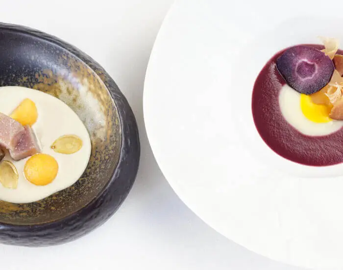 Two composed plates: one with tuna, melon balls and cream sauce, another with purple carrot and beet puree