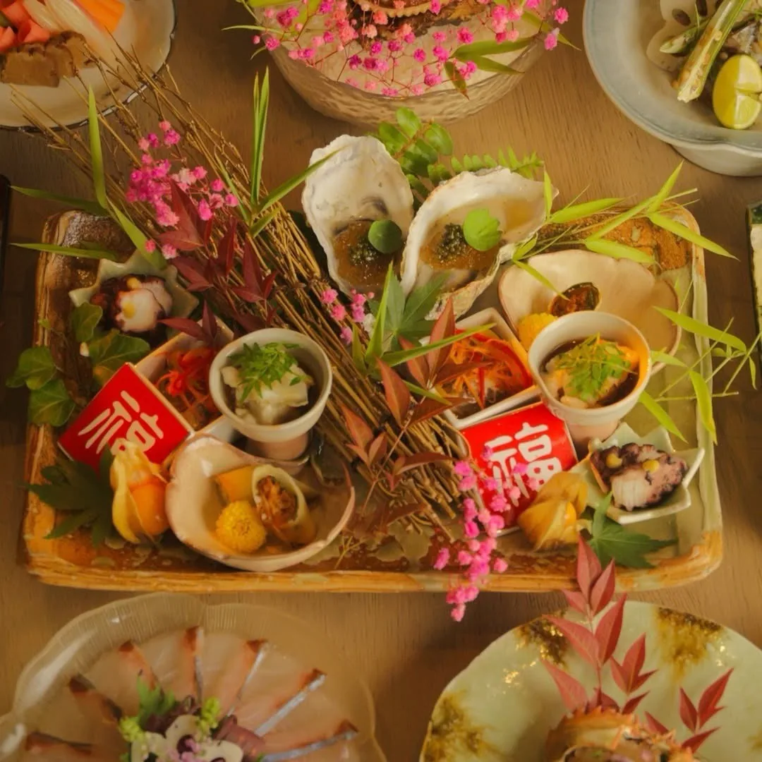 An overhead view of a platter of sashimi and small dishes with pink blossom garnish