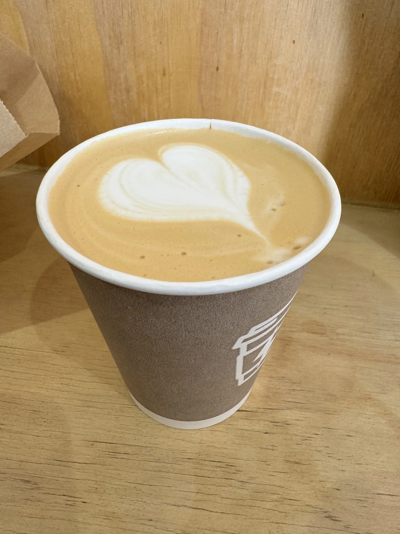 A latte with heart-shaped foam art in a paper cup