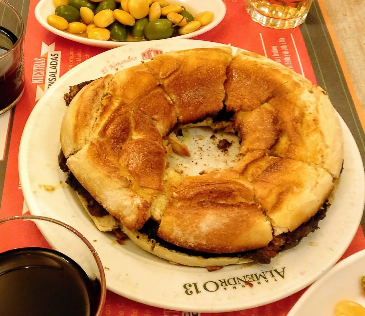 A round stuffed bread roll served on a plate with wine
