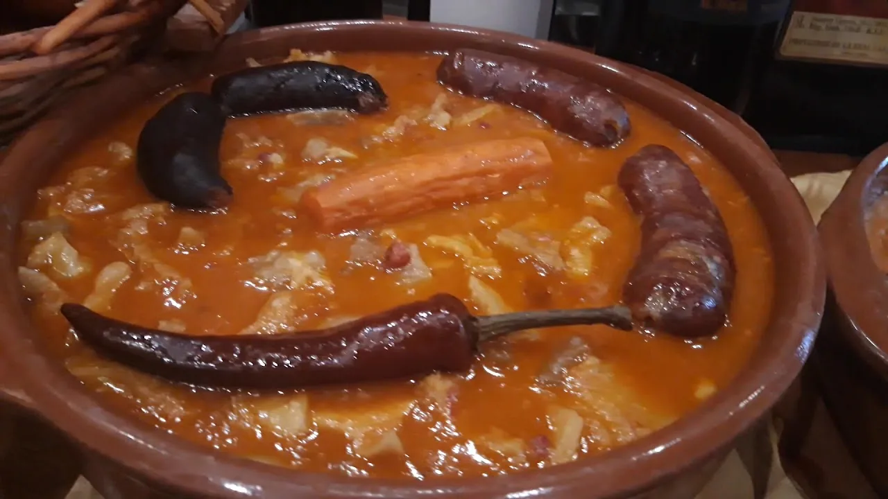 A terracotta dish of bean stew with blood sausage and chorizo