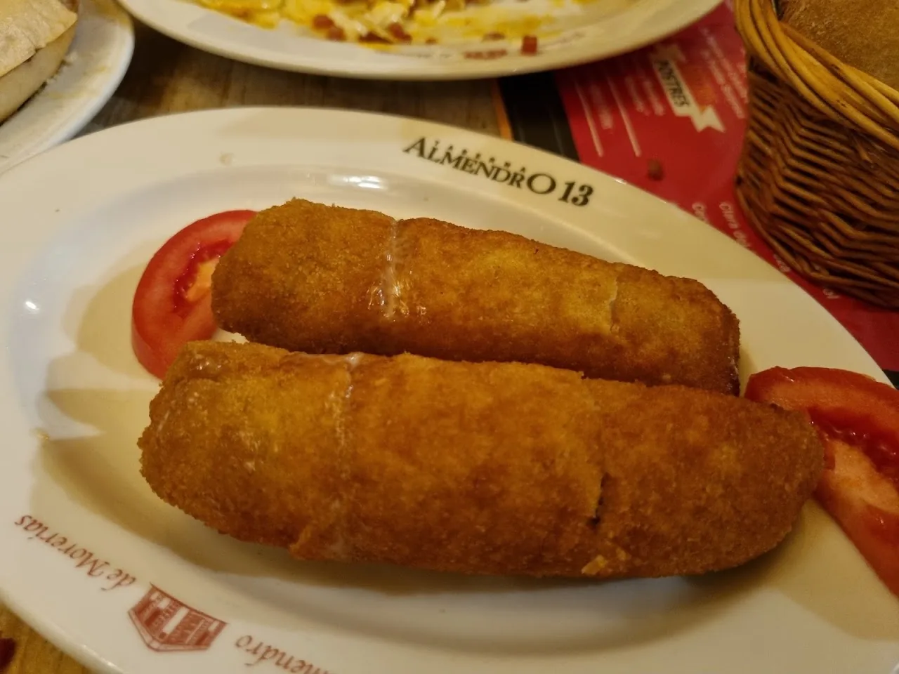 Two fried croquettes on a plate with tomato garnish