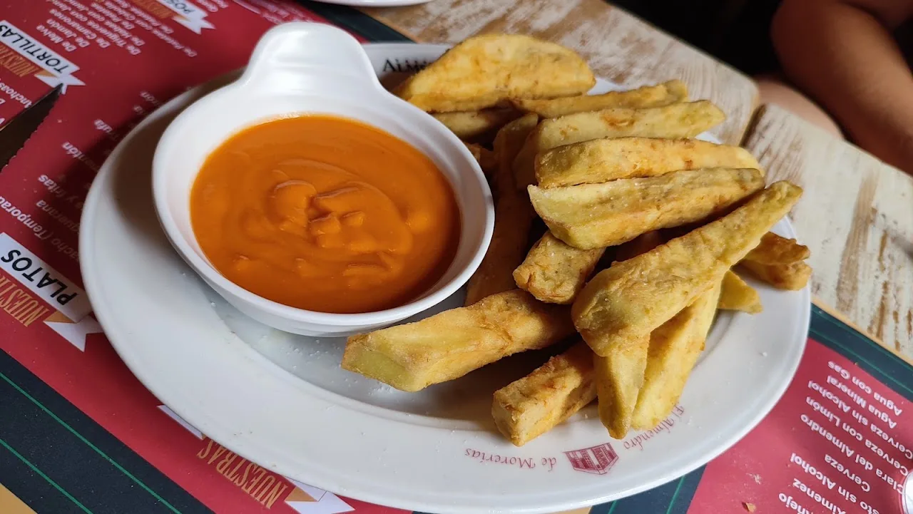 Fried potato wedges with a bowl of orange dipping sauce