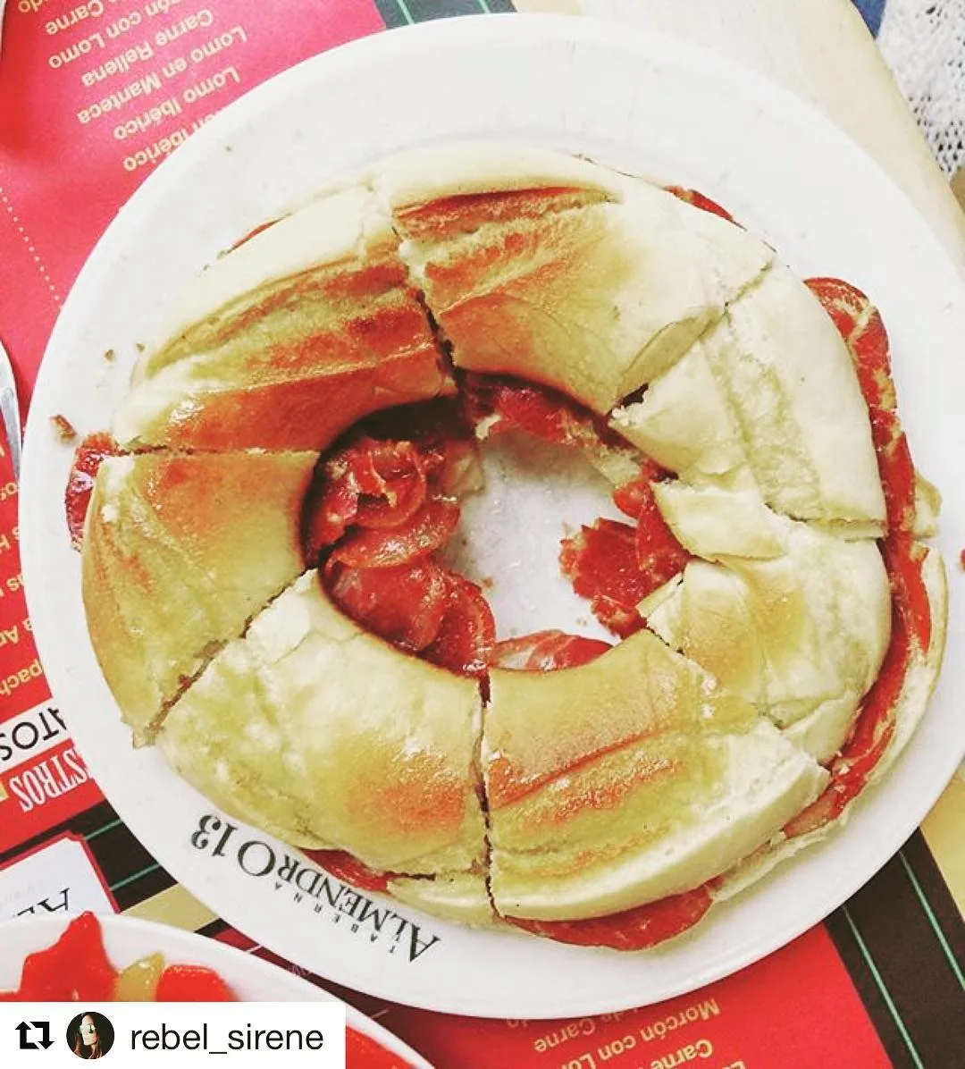 Round crusty bocadillo filled with red chorizo, cut into wedges on a plate
