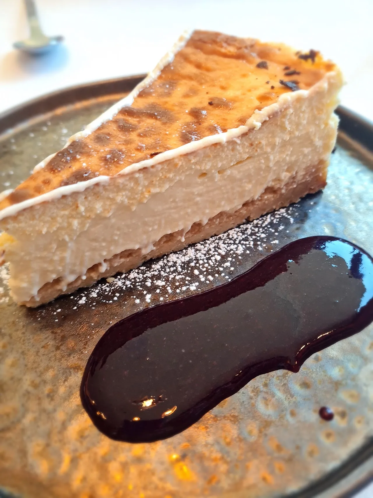 A slice of cheesecake with a dark chocolate sauce swirl