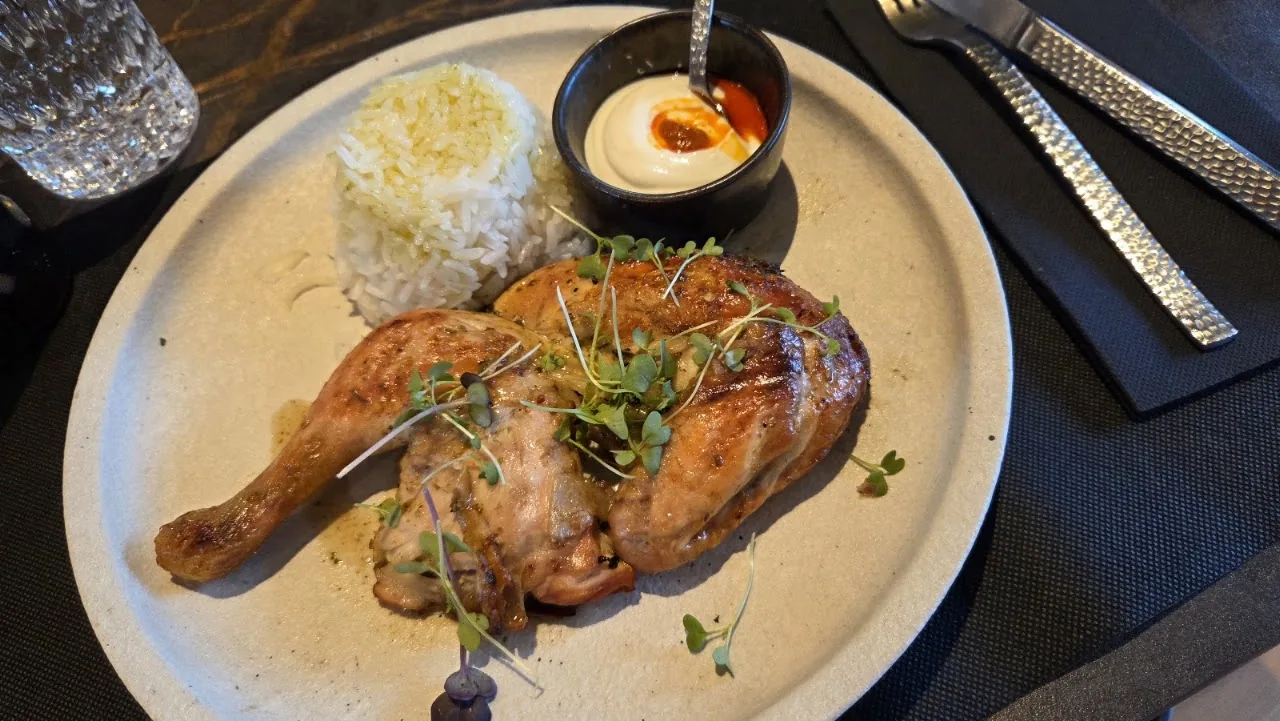 A roasted chicken leg with rice and a dipping sauce